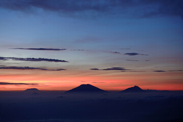 Fototapeta na wymiar Sunrise above the height with the silhouette of mountain ranges and dark blue sky turning bright