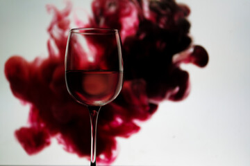 glass of wine wine glass filled with water on white background with an abstract red paint splash