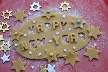 Happy New year.Cookie dough letters on wooden table with sugar snowflakes and colorful chocolate...