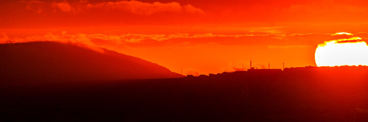 Obraz premium Red sun at sunset under the clouds above the horizon. Epic dramatic picture of the sky