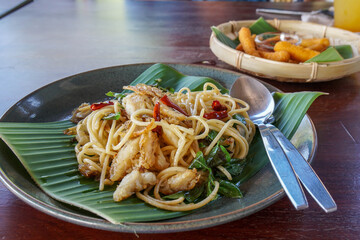 spicy spaghetti on banana leaf and round plate in restaurant