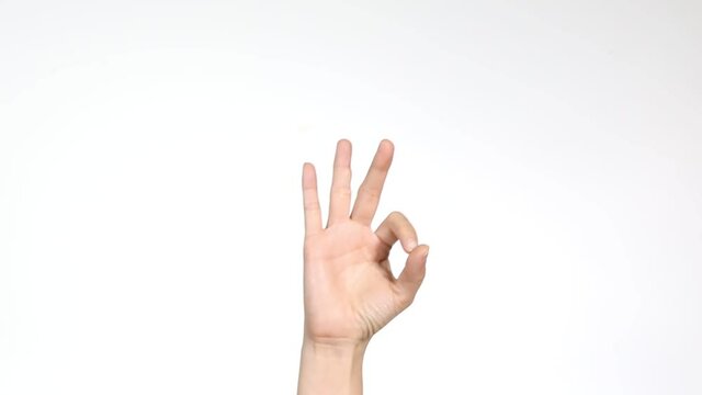 Unrecognizable female shows an ok sign on wall white background. Hand sign. Body language and meditation concept. With place for text or image, promotional content.