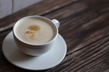 coffee in white cup with saucer on wooden table with wooden bottom