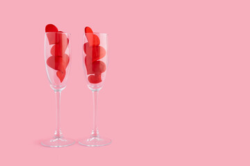 Two champagne glasses with red hearts for couple, man, woman on pink background. 14 february. Happy valentines day dinner. greeting card, banner. copy space, text