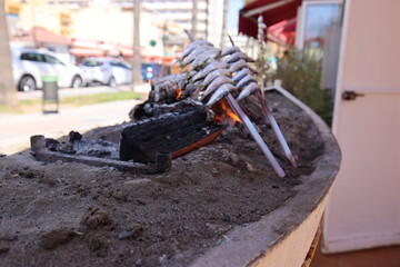 Elaboration of Malaga's espetos al carbón with the beach in the background. Sardines