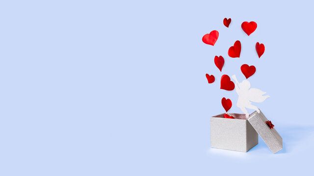 open silver gift box with flying out hearts and cupid on blue background. levitation. happy valentines day. symbol of 14 February. banner. copy space, place for text.