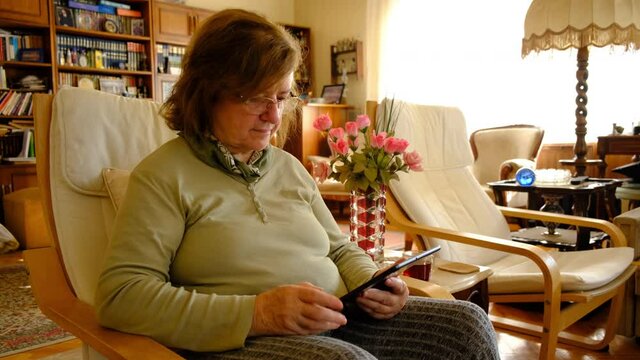 Tablet. Senior adult using digital technology device indoors. Touching screen.