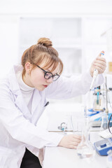 A laboratory assistant pours reagents into a flask using a special astomatic pipette. Assistant in the chemistry laboratory at the university