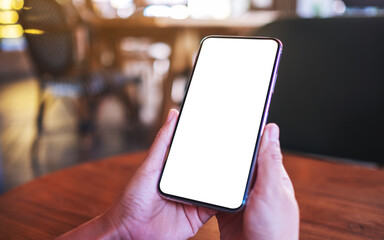 Mockup image of a woman holding mobile phone with blank white desktop screen