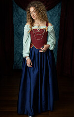 Fototapeta na wymiar A young renaissance woman wearing a red corset and blue silk skirt