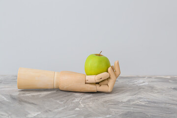 Wooden hand with apple on table