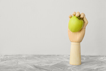 Wooden hand with apple on table