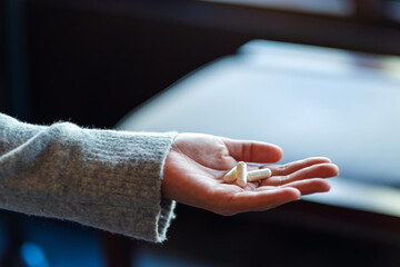 Closeup image of a woman holding white medicine capsules in hand