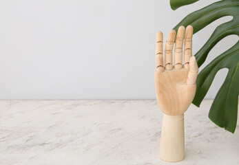 Wooden hand and monstera leaf on table