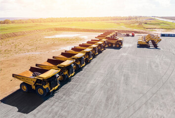 Large parking lot with big yellow mining truck, bulldozers for coal industry, ore and gold. Concept...