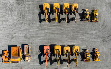 Large parking lot with big yellow mining truck, bulldozers for coal industry, ore and gold. Concept...
