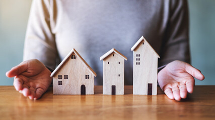 Closeup image of a woman showing wooden house models on the table