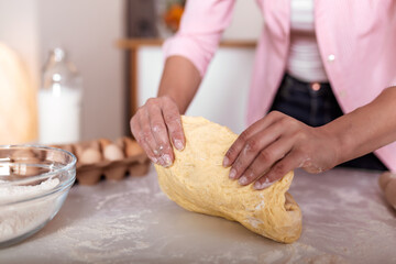 Close up of female baker hands kneading dough and making bread. cooking and home concept - close up of female hands kneading dough at home