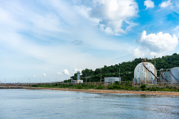 Naklejka premium Natural gas or fuel storage tank behind a hill on the coast on a clear day with blue sky