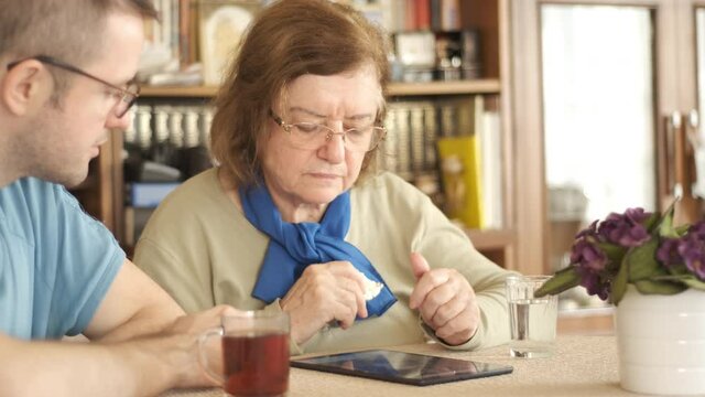 Tablet. Senior adult learning to use digital technology device. Touching screen.