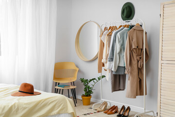 Interior of stylish bedroom with clothes rack