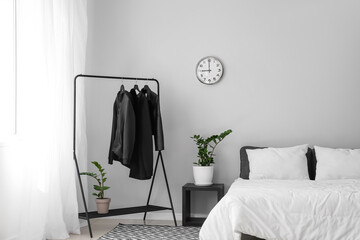 Interior of stylish bedroom with clothes rack