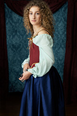 A young renaissance woman wearing a red corset and blue silk skirt