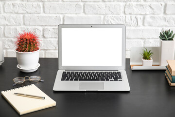 Stylish workplace with laptop near brick wall