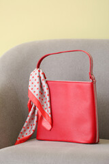 Stylish bag on armchair against color background
