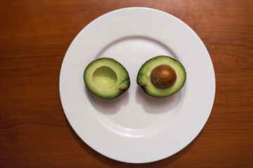 One sliced avocado on a white plate