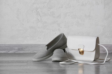 Stylish bag and shoes against gray wall