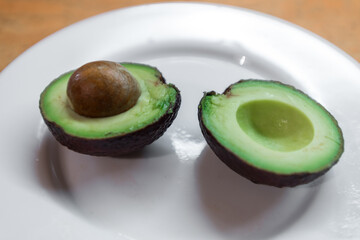 One sliced avocado on a white plate