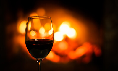 A glass of red wine on the background of the fireplace lights