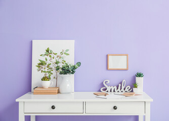 Stylish workplace with blank photo frame near color wall