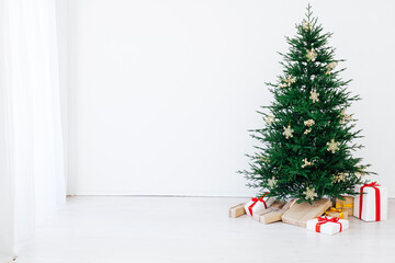 Christmas tree with new year gifts in a white room with a window