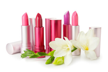 Different lipsticks and flower on white background
