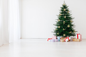 Christmas tree with new year gifts in a white room with a window