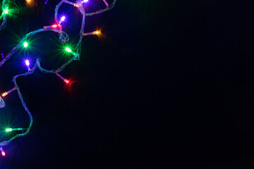 Christmas banner background. Glowing Christmas tree garland on dark background. Copy space. Festive background.