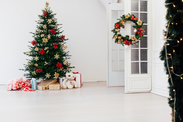 Christmas tree with new year gifts in a white room with a window
