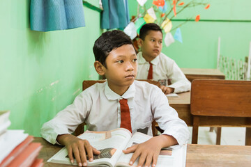 a portrait of an indonesian female student watching his teacher teaching in the class