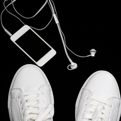 Sport Concepts. Pair of New White Sneakers Together with Music Player and Headphones On Black