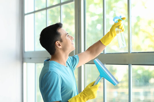 Young Man Cleaning Window At Home