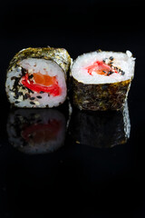Japanese Cuisine Ideas. Macroshot of Two Traditional Sushi Rolls With Salmon, Ginger and Orange Together on Black Reflective Surface.
