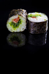Japanese Cuisine. Macro Shoot of Two Traditional Sushi Rolls With Salmon and Laminaria Together on Black Surface.