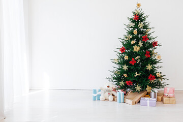 decorated Christmas tree with New Year's gifts in a room with a window