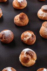 French profiteroles with cream. Many sweets on dark background.