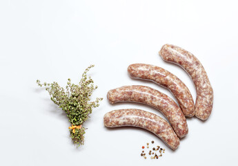 German raw bratwurst Pork Sausages on white with a bunch of thyme and multicolored pepper - seasoning