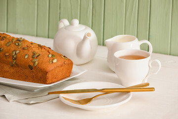 Tasty pumpkin pie with tea on table