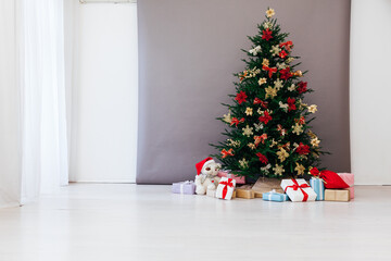 decorated Christmas tree with New Year's gifts in a room with a window