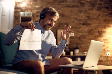 Happy businessman having conference call over laptop from home.